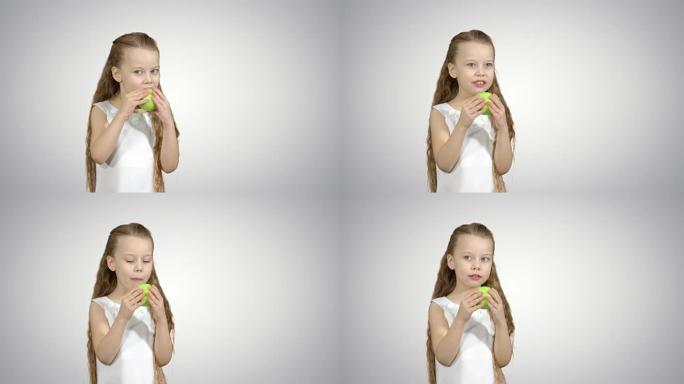 一个小女孩在白色背景上吃青苹果的肖像