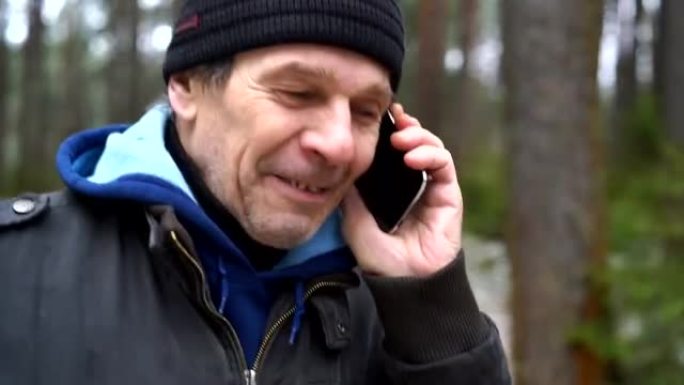 活跃的70岁老人在冬季森林中行走时通过手机聊天