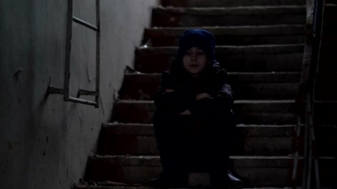 男孩独自坐在一栋破旧的破旧建筑中，拆除房屋，寒冷的天气