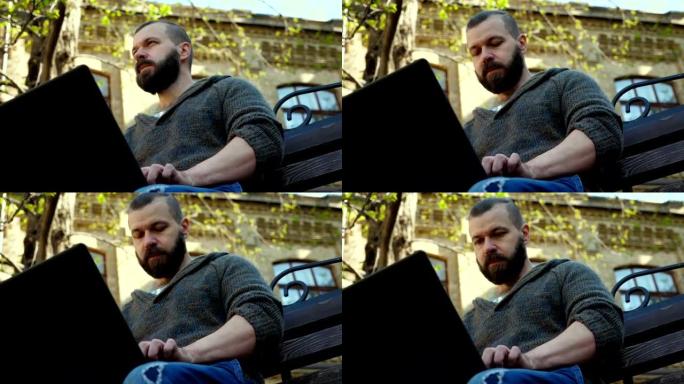 这位大胡子的人坐在公园的长椅上，在笔记本电脑上打印文字，想出了一个主意。