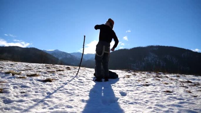 面目全非的年轻人在冬季山区跳舞滑稽。盖伊在白雪皑皑的风景背景下跳舞。男性游客在冬季大自然中玩耍。慢动