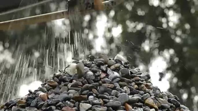 鹅卵石和石头在采石场的传送带上掉落在石头山上
