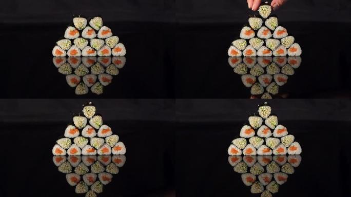 女孩把寿司放在黑色背景的金字塔上。