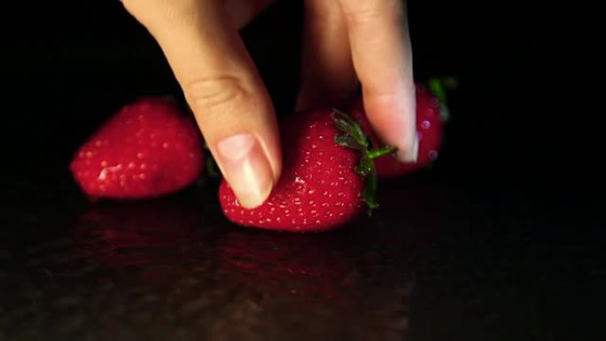 一只手拿一个表面潮湿的草莓浆果
