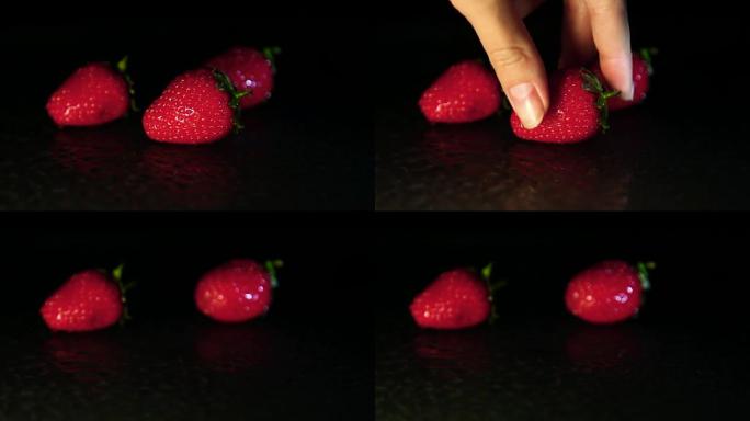 一只手拿一个表面潮湿的草莓浆果