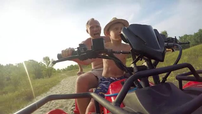 在一个阳光明媚温暖的日子里，爸爸和儿子在地形上开着一辆沙滩车的4K视频