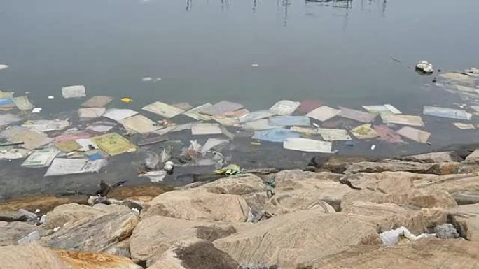 环境污染。河或湖中的塑料瓶、袋子、垃圾。漂浮在水中的垃圾和污染。沿着受污染的海岸运动。特写