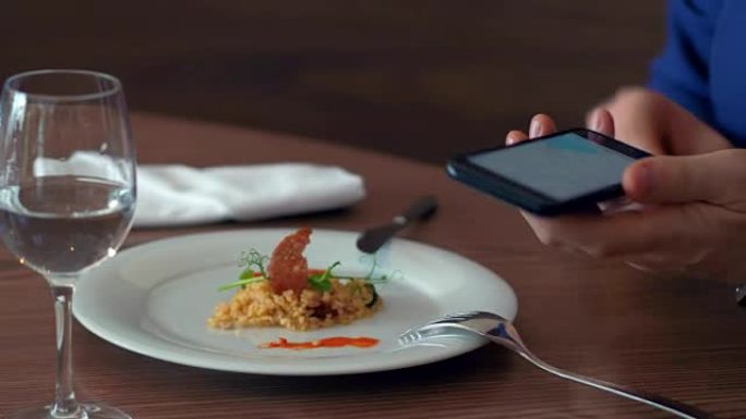 在咖啡馆的背景食物上进行商务午餐时，男性手使用手机