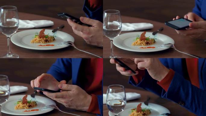 在咖啡馆的背景食物上进行商务午餐时，男性手使用手机