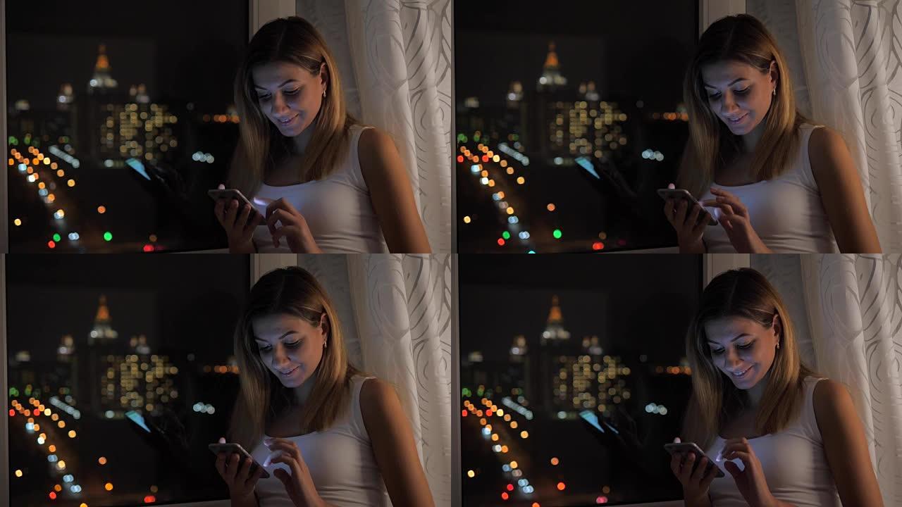 漂亮的女人站在窗前欣赏夜景，并使用智能手机