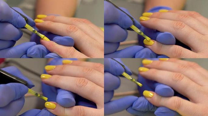 在手指甲上涂抹紫红油的特写镜头。美容院的手工修指甲过程。