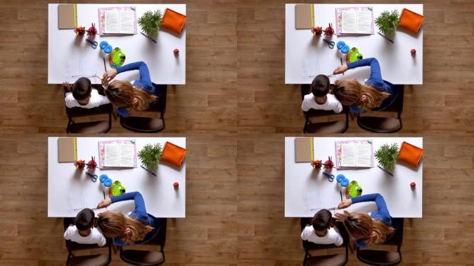 年轻的母亲和儿子一起画画，坐在桌子后面，孩子在做作业顶层拼花木地板