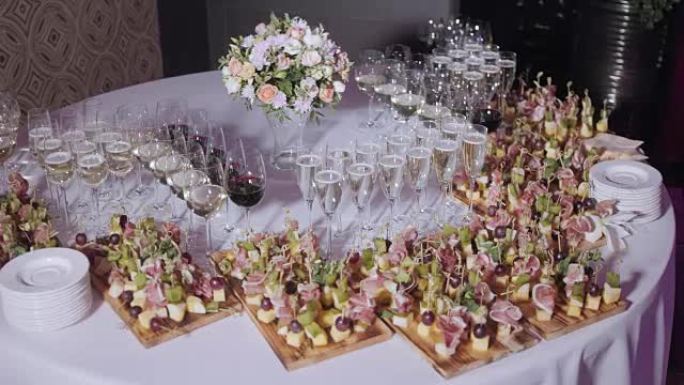 Furshet。桌面装满了一杯起泡的白葡萄酒，背景是小点心和开胃菜。香槟泡泡