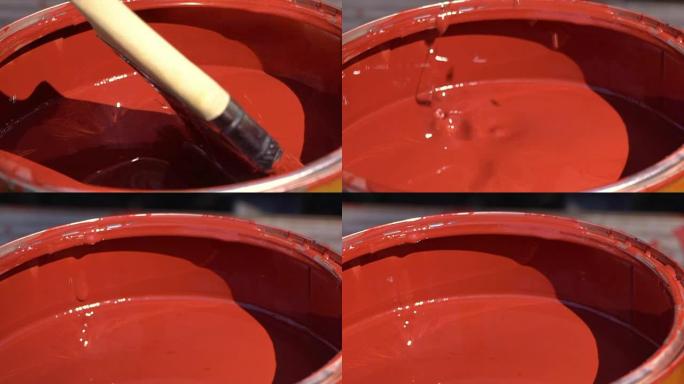 一个男人的手用油漆润湿罐子里的刷子的特写
