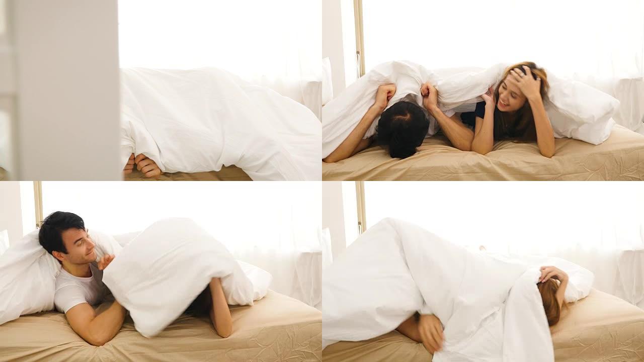 年轻幸福的夫妇躺在床上盖着毯子在家玩耍，睡前概念