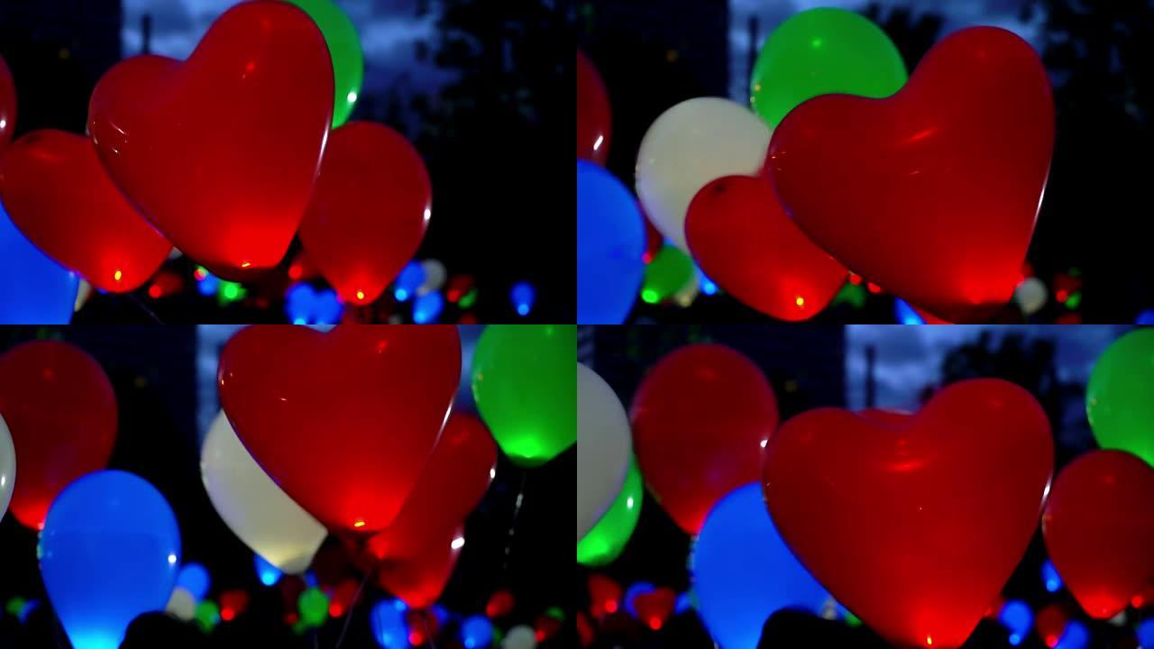 爱情盛宴的概念。黑色背景下飞行的发光彩色氦气发光气球，适合情人节、新年和圣诞节，红色心形气球形状