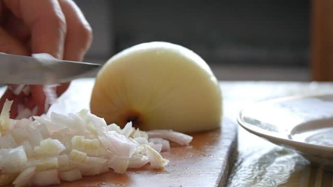 女手用刀在厨房板上切一个大洋葱