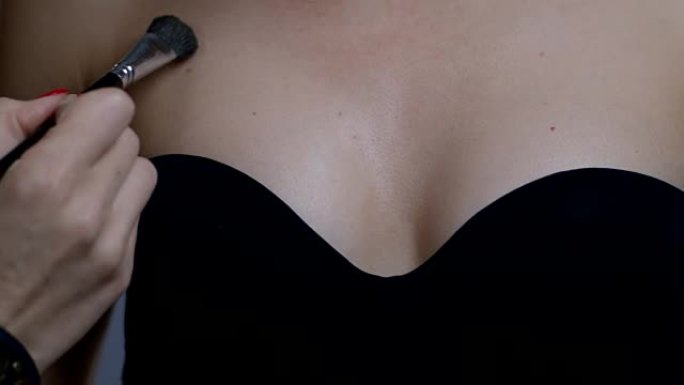 化妆师在时装模特的乳房上应用基础的后台。时尚视频。