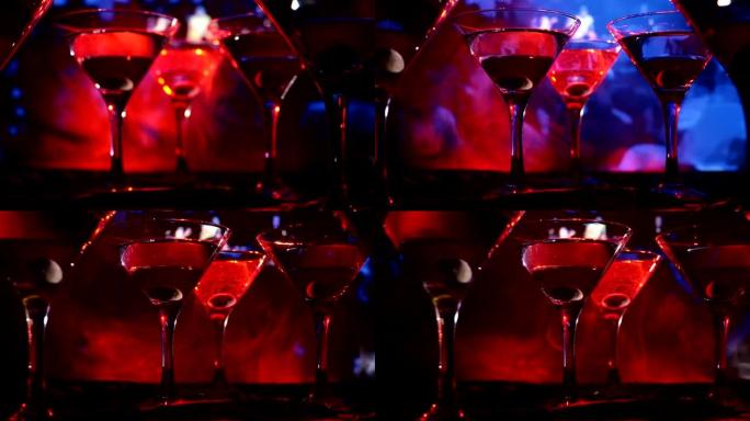 酒精饮料倒入马提尼酒杯中。几杯著名的鸡尾酒马提尼酒，在带有深色雾气背景和迪斯科灯光的酒吧拍摄。俱乐部