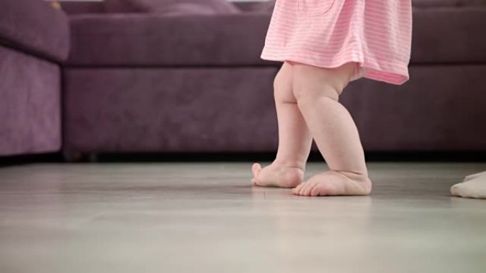女婴正在迈出人生的第一步。婴儿学习步行。小脚步