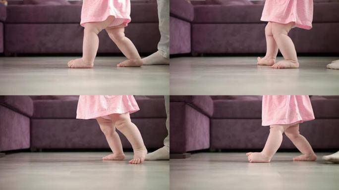 女婴正在迈出人生的第一步。婴儿学习步行。小脚步