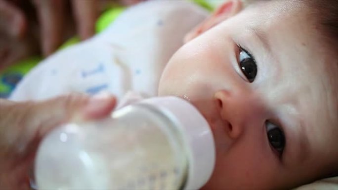 漂亮的男婴喝奶瓶里的牛奶