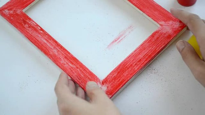 女人用海绵从木框上抹去油漆