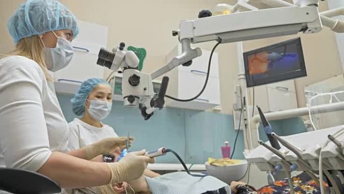 医生使用特殊的口内数码微型相机检查牙齿。在监视器上的牙医和患者看到牙齿，牙齿问题的视频。正畸医生使用