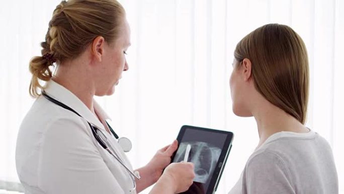 女医师在门诊给女性病人展示平板x光片。工作中的女专业医生