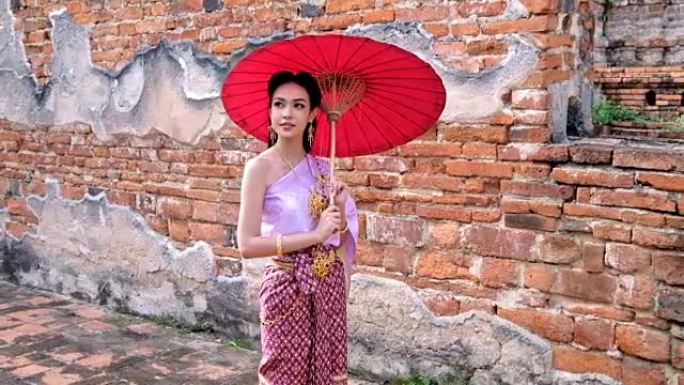 穿着泰国民族礼服的泰国年轻女子在联合国教科文组织世界历史名城大城府的老庙中行走。欢迎来到泰国概念。