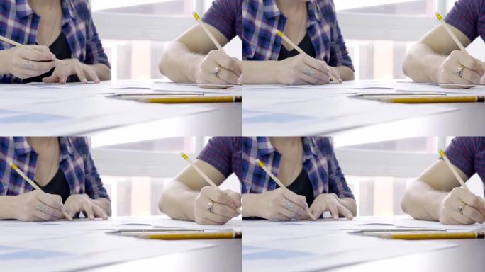 两个人在桌面上用铅笔在尺子上画一幅画