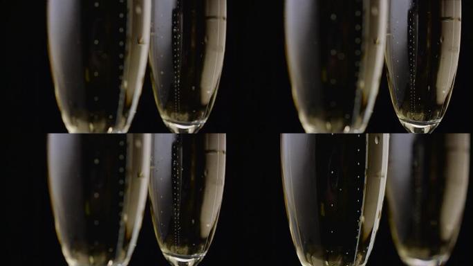 两杯香槟泡泡特写升起。黑色背景