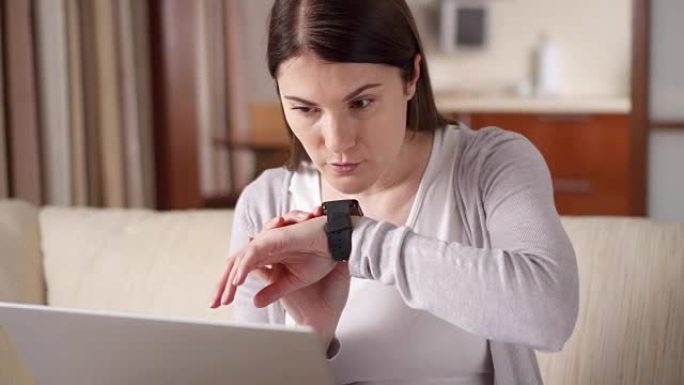 女人在家通过智能手表发送音频信息。从事智能手表的年轻女性专业人士