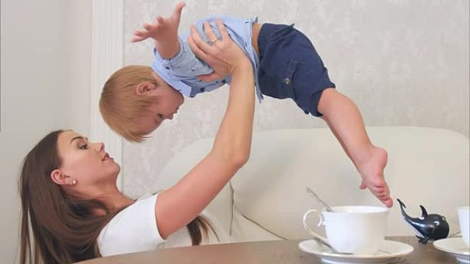 快乐的年轻母亲和坐在茶几旁的男婴玩耍