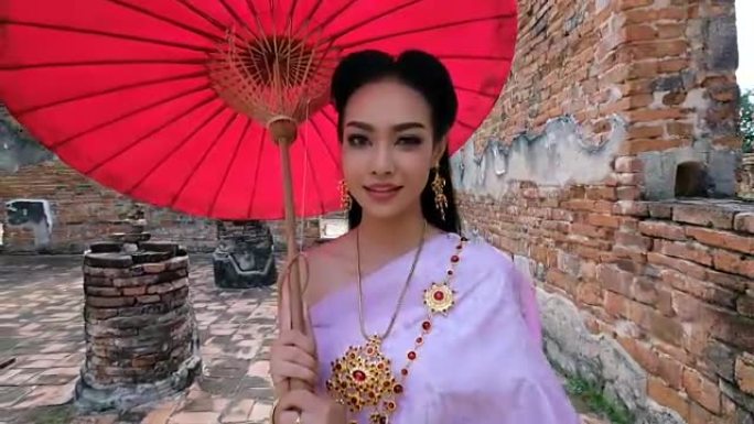 穿着泰国民族礼服的泰国年轻女子在联合国教科文组织世界历史名城大城府的老庙中行走。欢迎来到泰国概念。