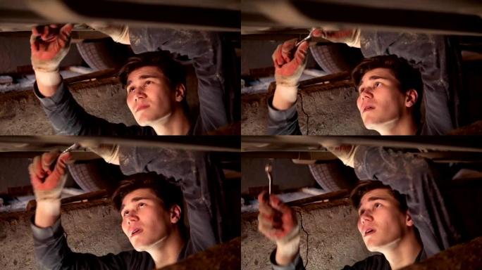 一辆正在修理汽车的汽车下面的男机械师