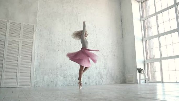 芭蕾舞演员穿着经典的芭蕾舞短裙和脚尖鞋旋转。一位年轻的芭蕾舞演员在大窗户的背景下踮起脚尖跳舞。慢动作