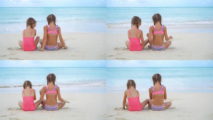 可爱的小女孩在沙滩上玩沙子。孩子们坐在浅水里做沙堡