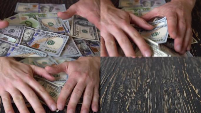 手在木桌上耙美元钞票，钞票背景