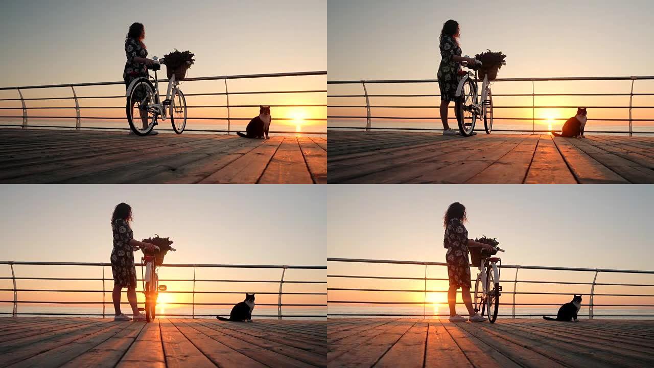 年轻迷人的女人穿着复古自行车和淡紫色花束，在日出或日落时靠近海边。女孩钦佩黎明，享受着在海洋海岸上生