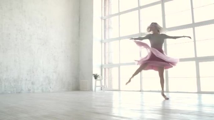 芭蕾舞演员穿着芭蕾舞短裙和脚尖鞋旋转并跳高。年轻的芭蕾舞演员在跳舞。慢动作
