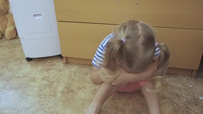 哭泣的小女孩坐在房间的地板上。