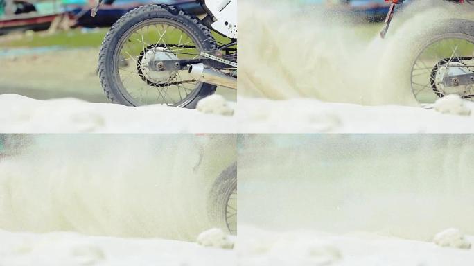 越野摩托车的轮子开始旋转，扬起地面和沙子