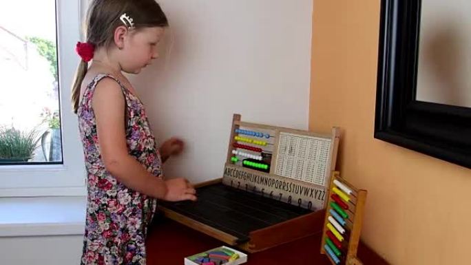 可爱的小女孩玩算盘，用粉笔在黑板上写字。学前概念，童年概念。捷克字母的玩具算盘。像学龄前儿童一样可爱