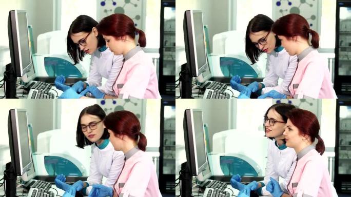 两名女性实验室工作人员使用计算机操作分析机器