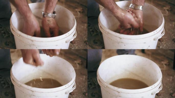 一名男子在完成工作后正在用水桶里的脏水洗手