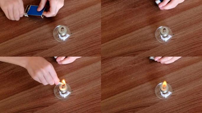 在家进行化学实验。特写男孩的手用火柴点燃了燃烧的酒精灯。
