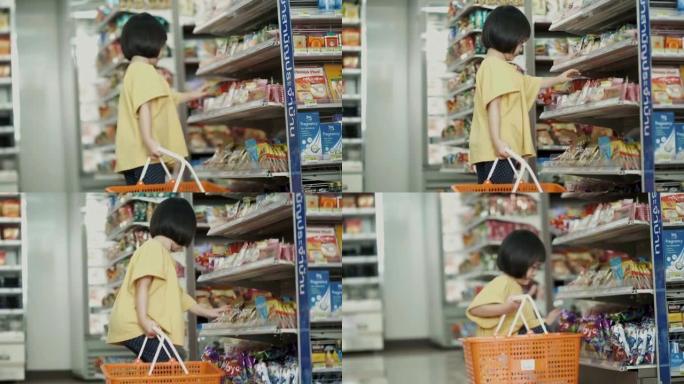 泰国小女孩的注意力集中在超市选择和购买一些食物