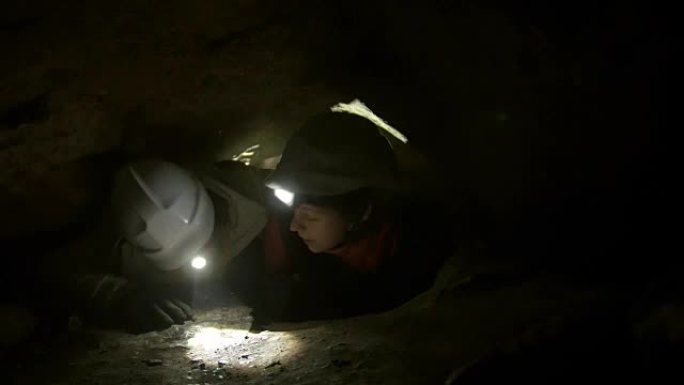 两名年轻的徒步旅行者探险家被困在黑暗洞穴的狭窄洞中