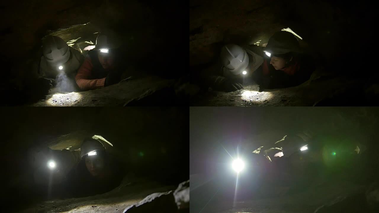 两名年轻的徒步旅行者探险家被困在黑暗洞穴的狭窄洞中